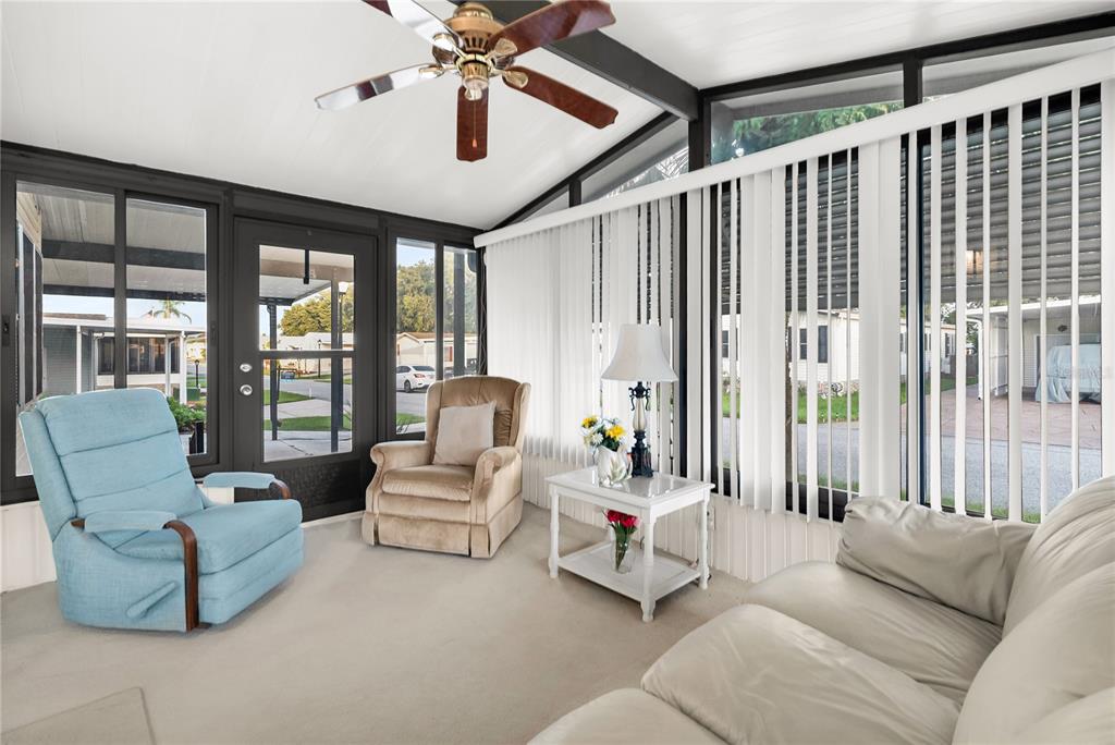 A sunroom features a ceiling fan, light-colored carpet, vertical blinds, and views of a neighborhood — 222 SUE AVENUE, DAVENPORT, FL