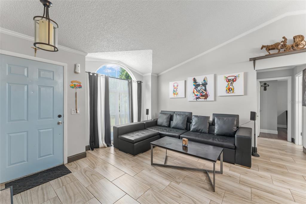 A living room with a black sectional sofa, coffee table, and an adjacent dining area — 961 MILLENBECK AVENUE, DELTONA, FL