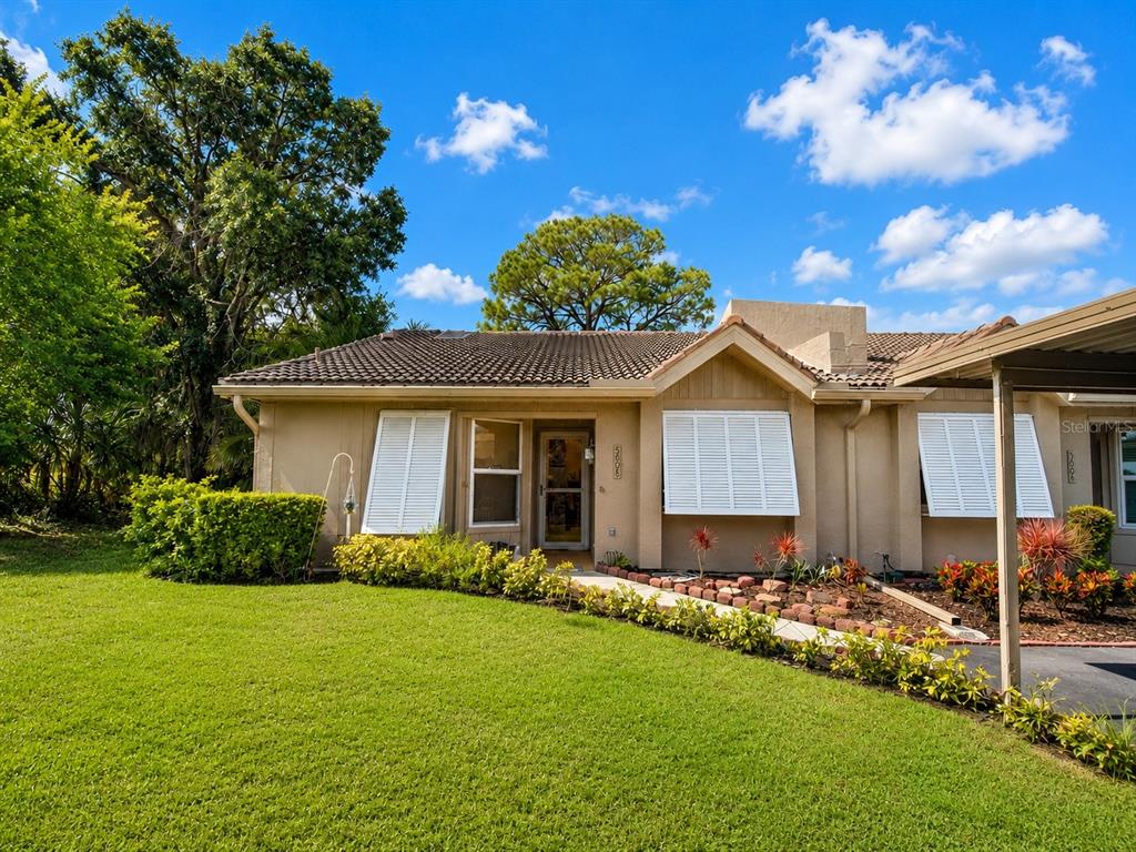 A single-story house with a tan stucco exterior, tile roof, and white shutters — 5608 37TH STREET E UNIT 26, BRADENTON, FL