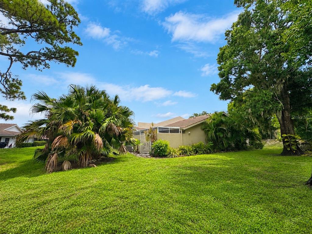 A view of a tan house exterior with a palm tree and a large lawn — 5608 37TH STREET E UNIT 26, BRADENTON, FL