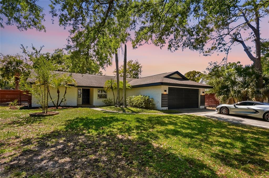 A single-story house with a white stucco exterior, dark garage door, and a paved driveway — 4606 BUCKEYE ROAD, TAMPA, FL