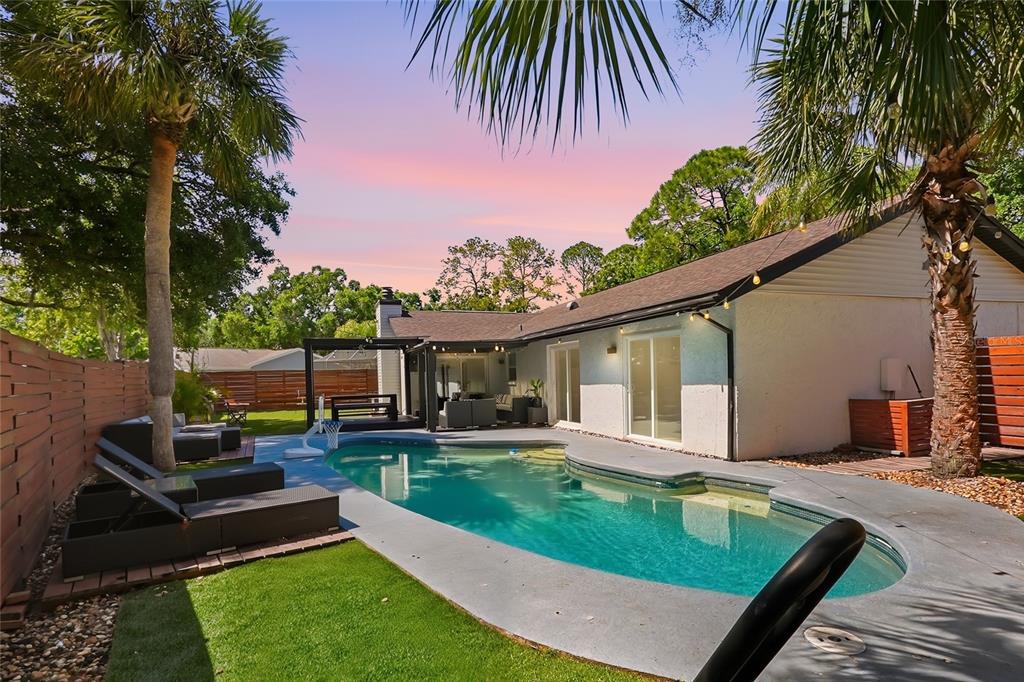 A backyard features a swimming pool, patio furniture, palm trees, and a white house exterior — 4606 BUCKEYE ROAD, TAMPA, FL