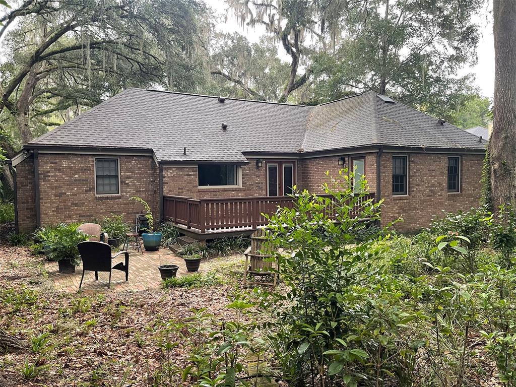 A brick house with a wooden deck and a brick patio in a wooded backyard — 8613 SW 55TH PLACE, GAINESVILLE, FL