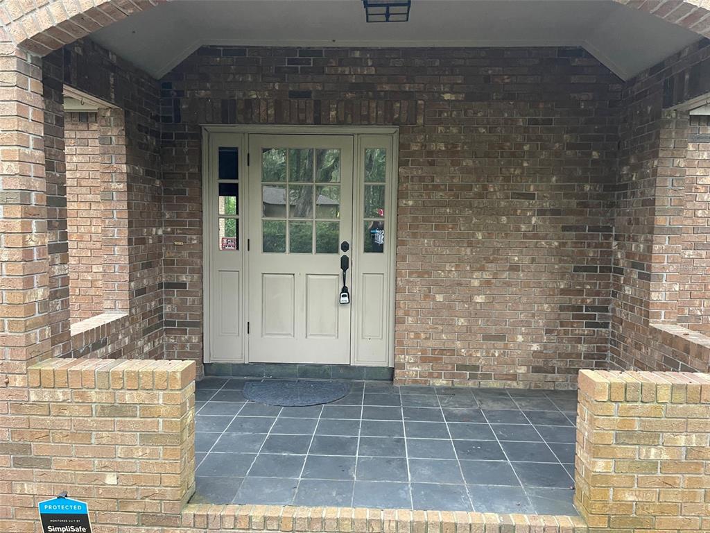 A brick-walled front porch features a tiled floor and a central door with sidelights — 8613 SW 55TH PLACE, GAINESVILLE, FL