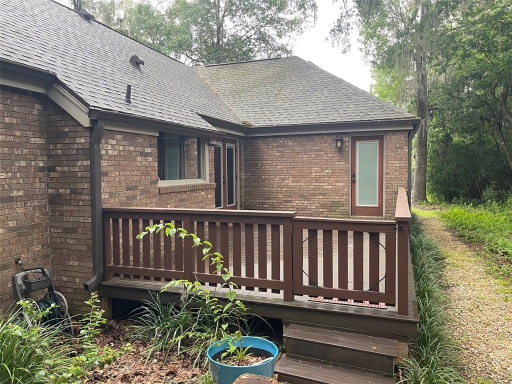 A brick house exterior features a wooden deck with railings and steps leading to a yard — 8613 SW 55TH PLACE, GAINESVILLE, FL