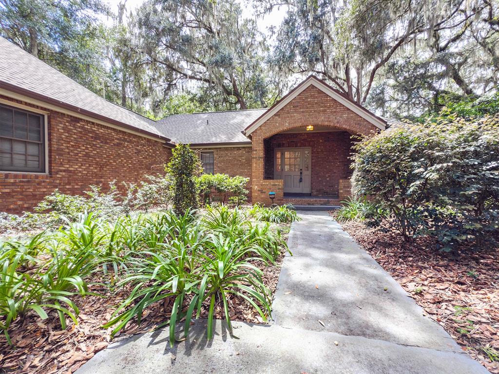 A brick house with a covered entryway and a concrete walkway surrounded by landscaping — 8613 SW 55TH PLACE, GAINESVILLE, FL