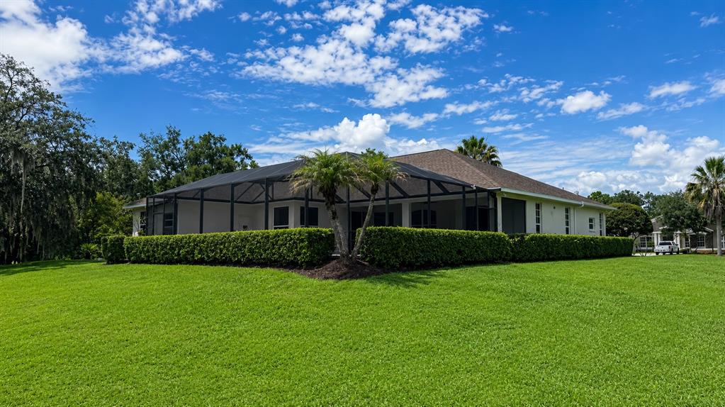 A single-story house with a screened-in lanai and a manicured hedge in the backyard — 22409 76TH AVENUE E, BRADENTON, FL