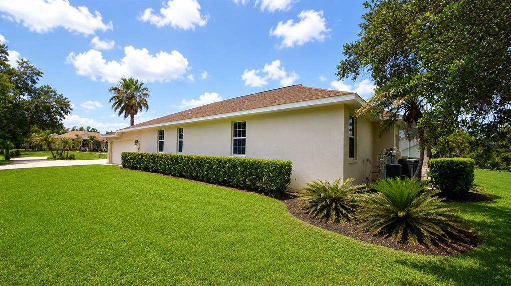 A side view of a beige house with a brown roof and a manicured lawn — 22409 76TH AVENUE E, BRADENTON, FL