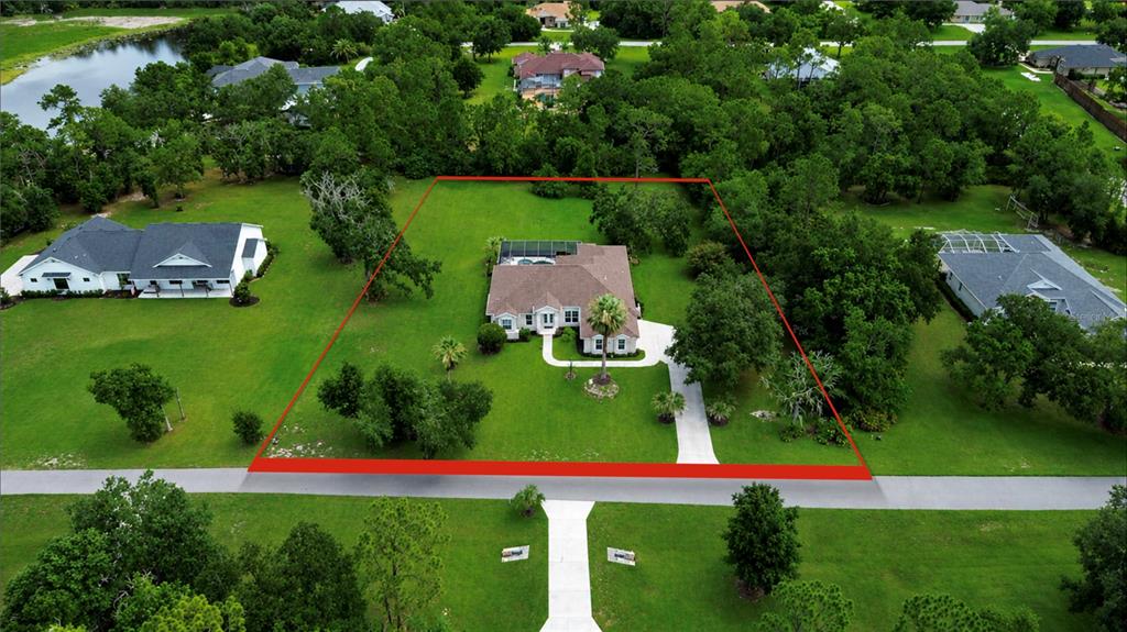 An aerial view shows a single-story house with a pool enclosure on a large lot — 22409 76TH AVENUE E, BRADENTON, FL