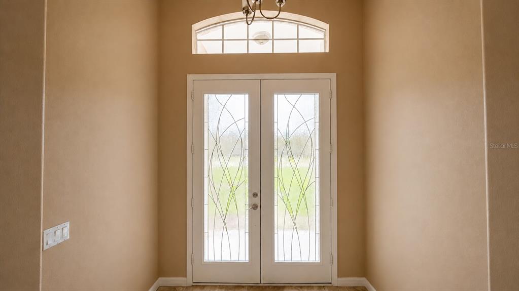 An interior view of a foyer featuring double glass-paneled doors and an arched transom window — 22409 76TH AVENUE E, BRADENTON, FL