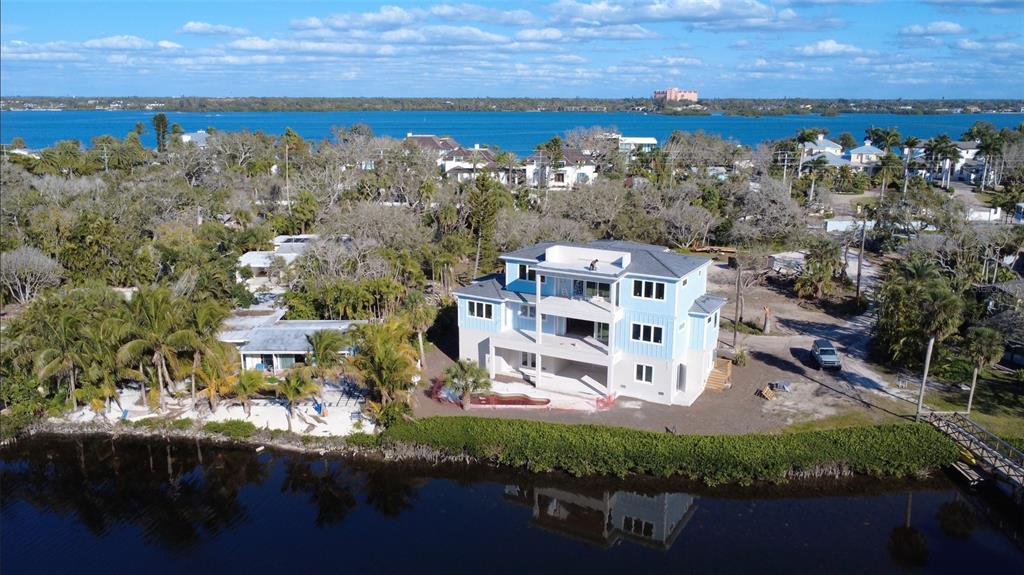 An aerial view of a multi-story light blue house under construction near a waterfront — 8534 HERON LAGOON CIRCLE, SARASOTA, FL