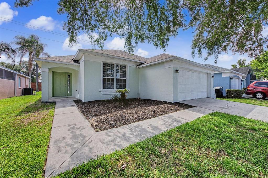A single-story house with a light green door, white garage, and a front lawn — 421 HOLBORN LOOP, DAVENPORT, FL