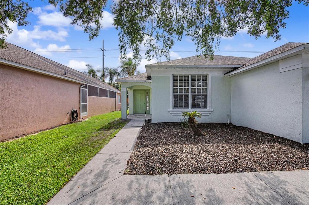 A light green house with a concrete walkway leading to a green front door — 421 HOLBORN LOOP, DAVENPORT, FL