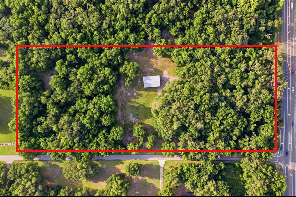 An aerial view shows a rectangular lot with a small building surrounded by dense trees — 7112 MARSH BEND TRAIL, WILDWOOD, FL