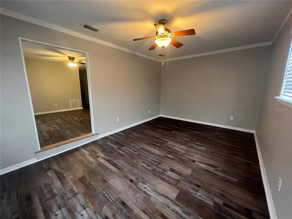 An empty room with gray walls, dark wood-look flooring, and a ceiling fan — 610 PATLIN AVENUE, ORANGE CITY, FL