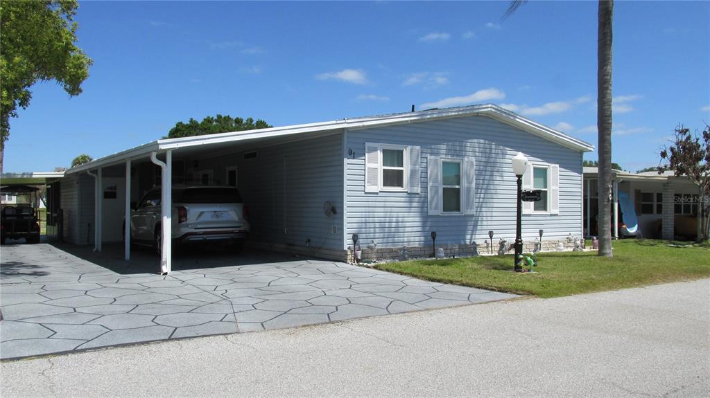 A light blue manufactured home with a carport and a patterned concrete driveway — 91 STRAPHMORE DRIVE, HAINES CITY, FL
