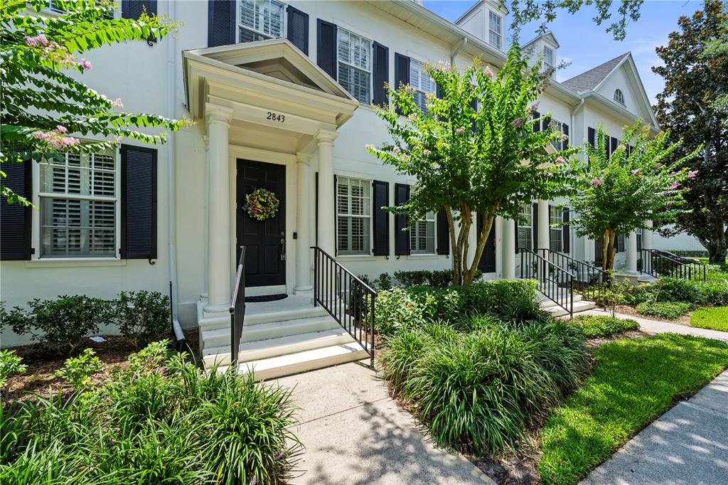 A white townhouse exterior features a covered entryway with columns and black shutters — 2843 UPPER PARK ROAD, ORLANDO, FL