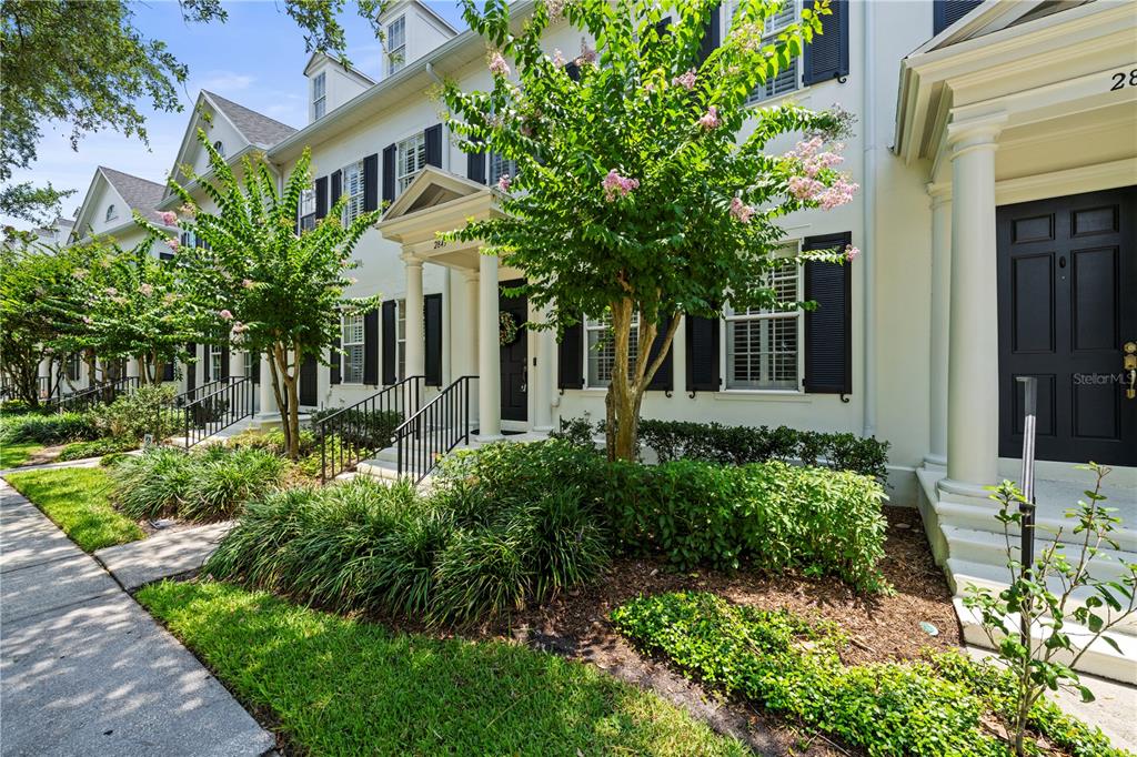 A row of white townhouses with black shutters and small front porches shaded by trees — 2843 UPPER PARK ROAD, ORLANDO, FL