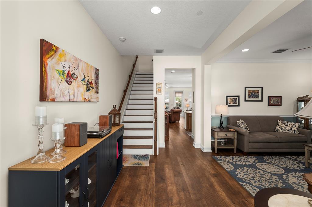 A foyer with a staircase, dark wood flooring, and a blue cabinet leads to a living room — 2843 UPPER PARK ROAD, ORLANDO, FL
