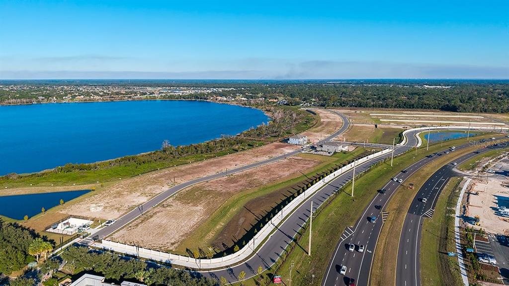 An aerial view shows a vacant residential lot next to a lake and a highway — 19293 LOCHSIDE LANE, MOUNT DORA, FL