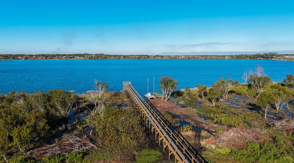 An aerial view shows a long wooden dock extending into a large, calm blue lake — 19293 LOCHSIDE LANE, MOUNT DORA, FL