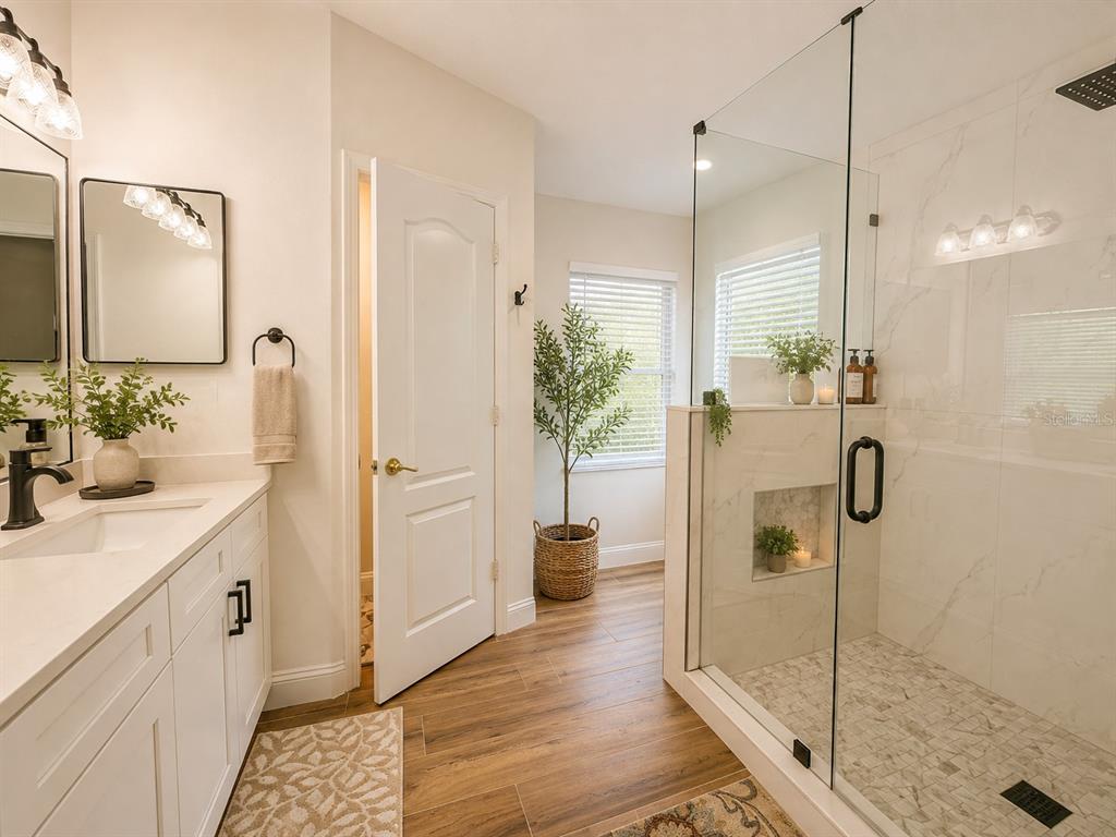 A bathroom features a white vanity, a glass-enclosed walk-in shower, and wood-look tile flooring — 25546 BRUFORD BOULEVARD, LAND O LAKES, FL