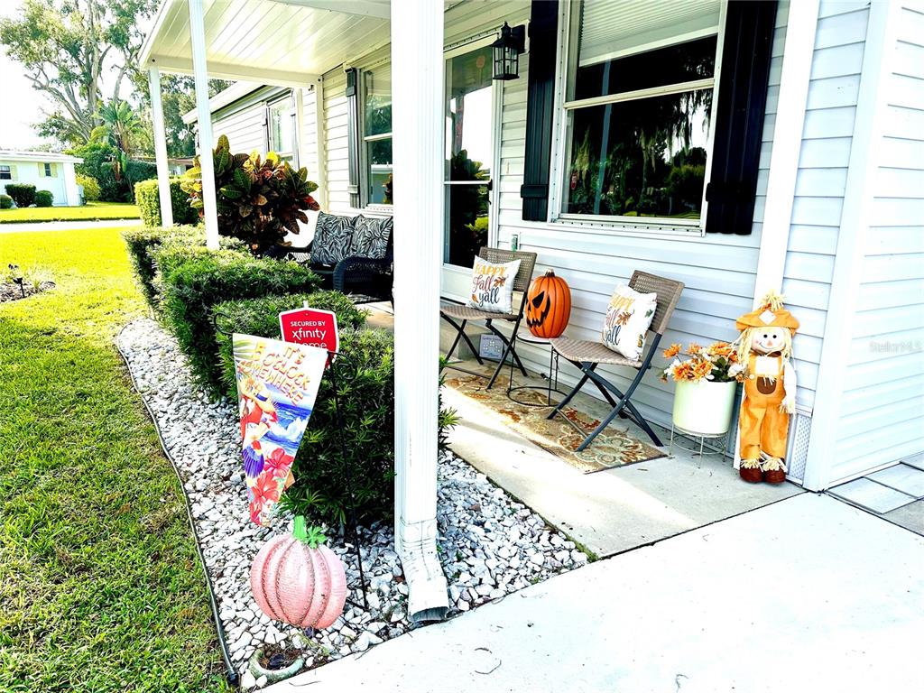 A front porch features two chairs, fall-themed decor, and a small garden bed with gravel — 2409 VINDALE ROAD, TAVARES, FL