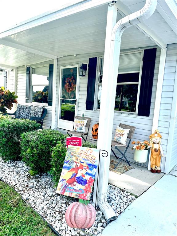 A covered porch features a front door, two chairs, fall decorations, and a garden sign — 2409 VINDALE ROAD, TAVARES, FL