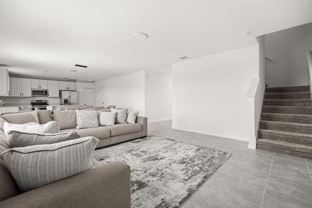 A living room with a gray sectional sofa, area rug, and stairs leading to the upper level — 4981 WORCHESTER DRIVE, KISSIMMEE, FL