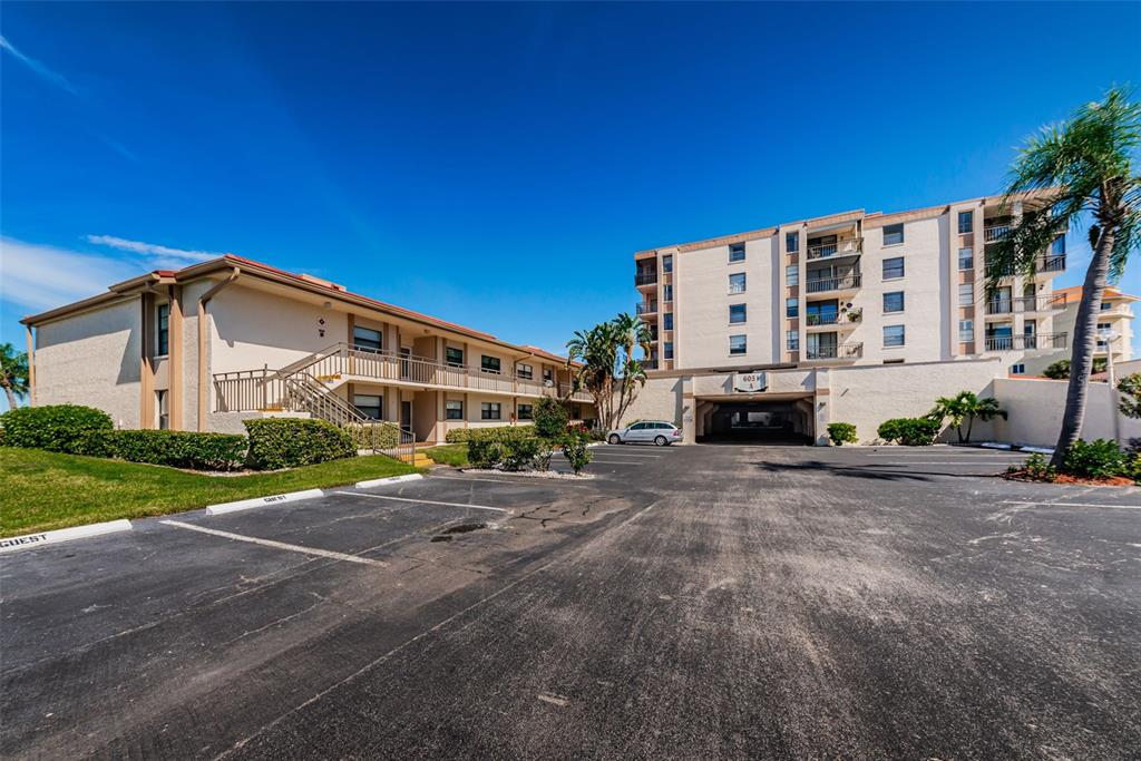 An exterior view of a multi-story apartment complex with a parking lot in front — 6051 SUN BOULEVARD UNIT 305, ST PETERSBURG, FL