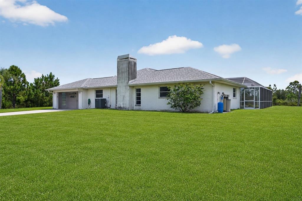 A single-story house with a white stucco exterior, a large chimney, and a screened-in patio — 5300 CYPRESS GROVE, PUNTA GORDA, FL
