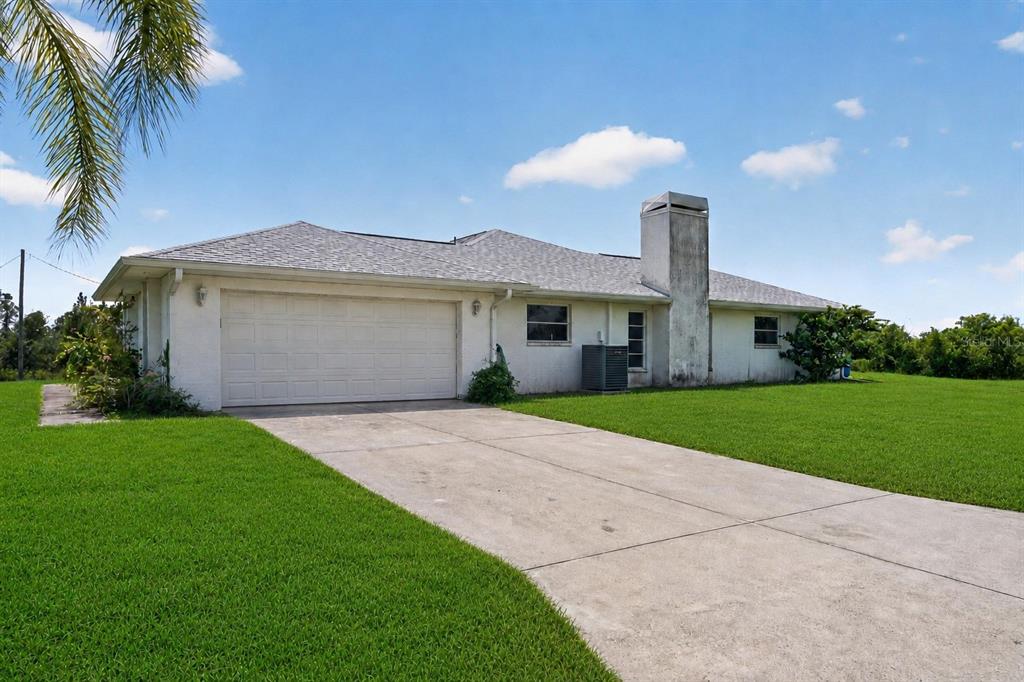 A single-story house with a white exterior, a two-car garage, and a large concrete driveway — 5300 CYPRESS GROVE, PUNTA GORDA, FL