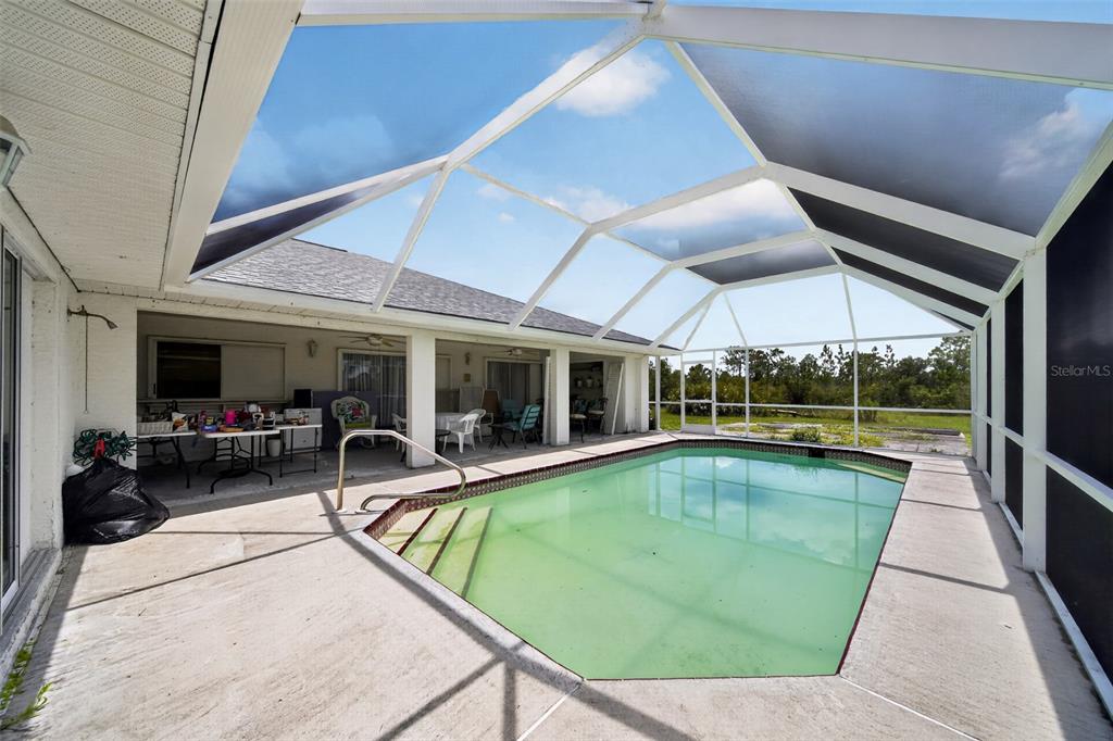 A screened-in patio features a swimming pool with steps and a concrete deck — 5300 CYPRESS GROVE, PUNTA GORDA, FL