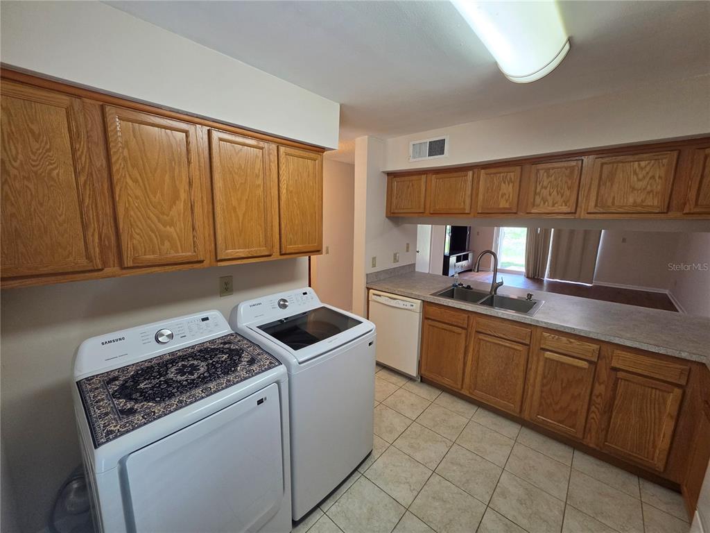 A kitchen with wood cabinets, tile floors, and a laundry area with white appliances — 5202 SUNRIDGE PALMS DRIVE UNIT 5202, TAMPA, FL