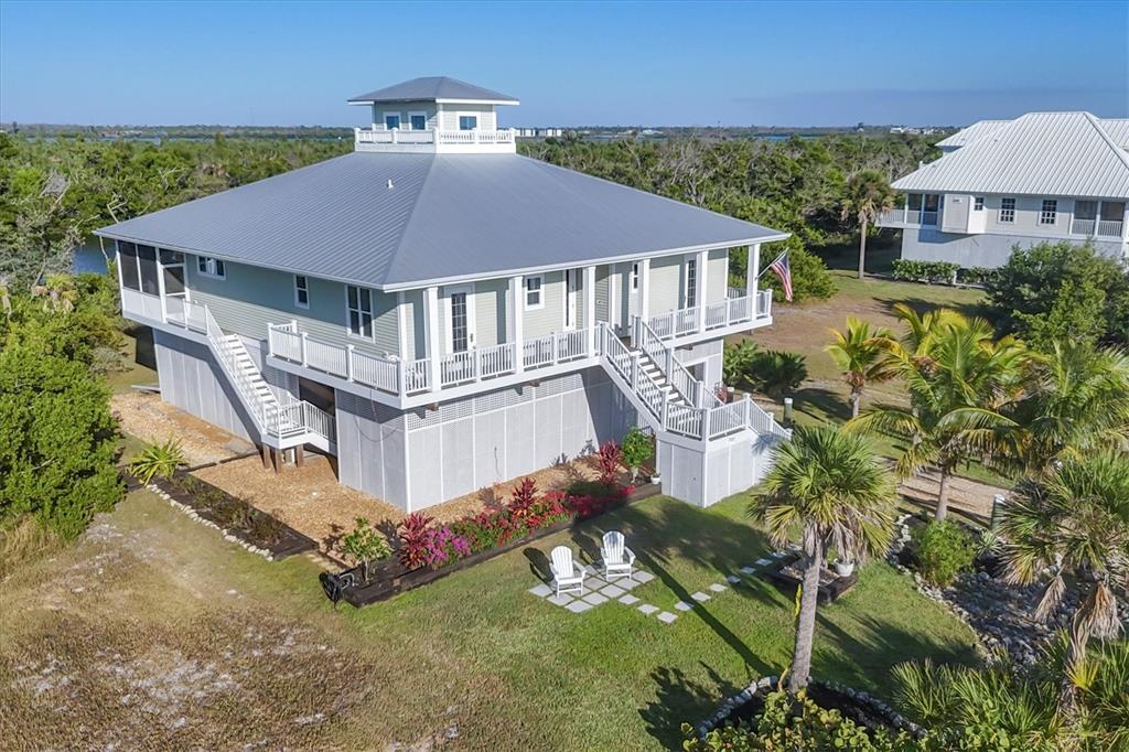 An elevated coastal house with a metal roof, wraparound porch, and a cupola — 7121 RUM BAY DRIVE, PLACIDA, FL