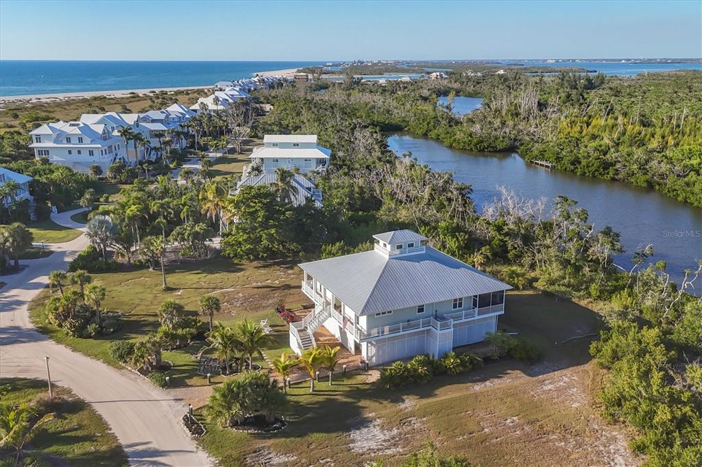 An aerial view shows a coastal house with a metal roof near a waterway — 7121 RUM BAY DRIVE, PLACIDA, FL