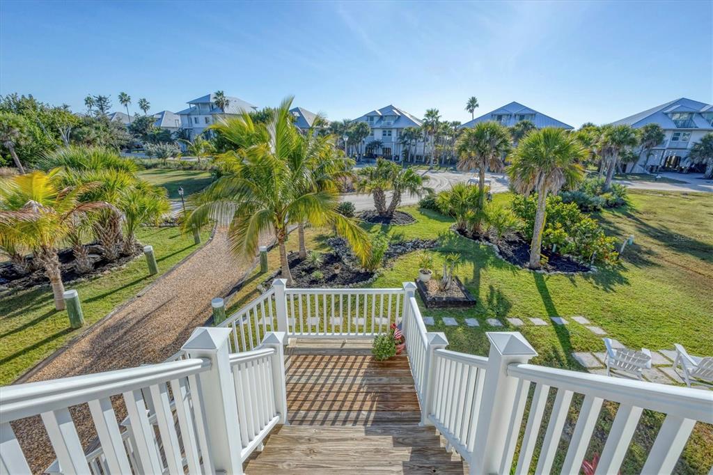 An elevated wooden staircase leads down to a landscaped yard with palm trees and houses — 7121 RUM BAY DRIVE, PLACIDA, FL