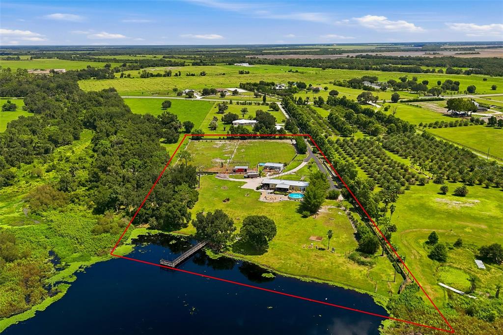An aerial view shows a house with a pool and dock on a large rural lot — 25916 STATE ROAD 64 E, MYAKKA CITY, FL