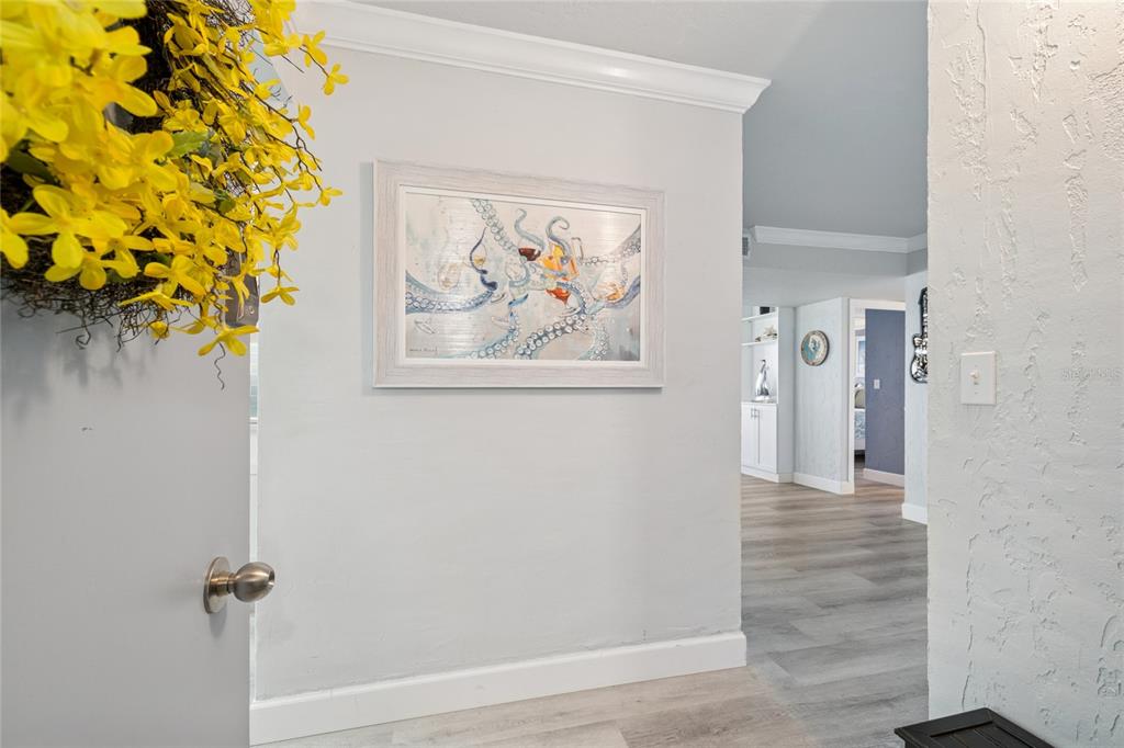 A view from a doorway into a hallway with light flooring and octopus wall art — 1 KEY CAPRI UNIT 101E, TREASURE ISLAND, FL