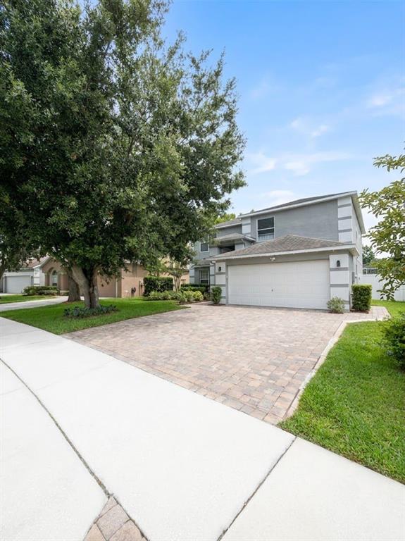 A two-story gray house with a paved driveway and a large tree in the front — 389 LAKEPARK TRAIL, OVIEDO, FL