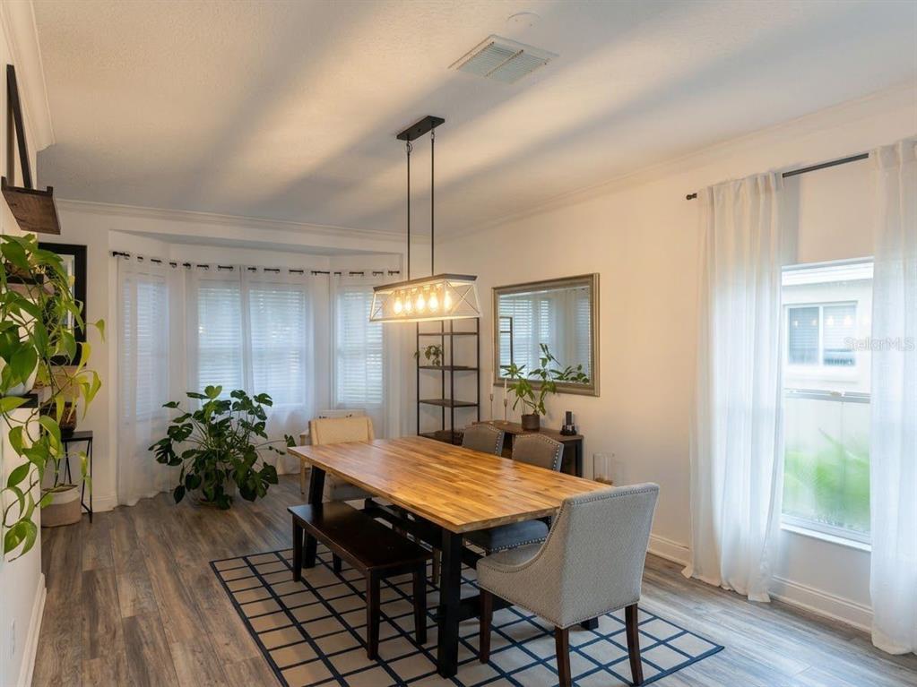 A dining room features a wooden table, a bench, upholstered chairs, and a modern light fixture — 389 LAKEPARK TRAIL, OVIEDO, FL