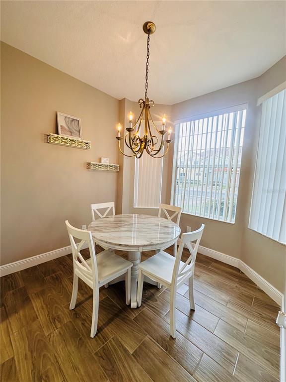 A dining area features a round marble-top table, four white chairs, and a brass chandelier — 1204 S BEACH CIR, KISSIMMEE, FL