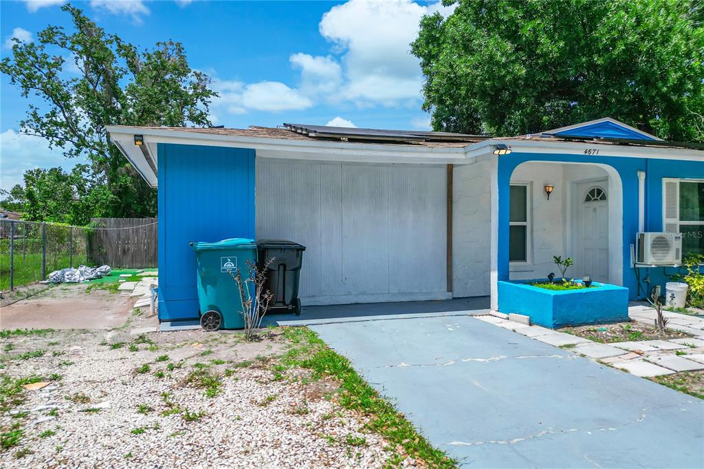 A single-story house with a blue exterior, solar panels, and a large tree in front — 4671 VERGARA COURT, ORLANDO, FL