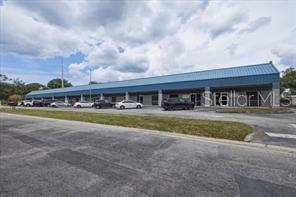 A long, single-story commercial building with a blue metal roof and a paved parking lot — 1882 PORTER LAKE DRIVE UNIT 106, SARASOTA, FL