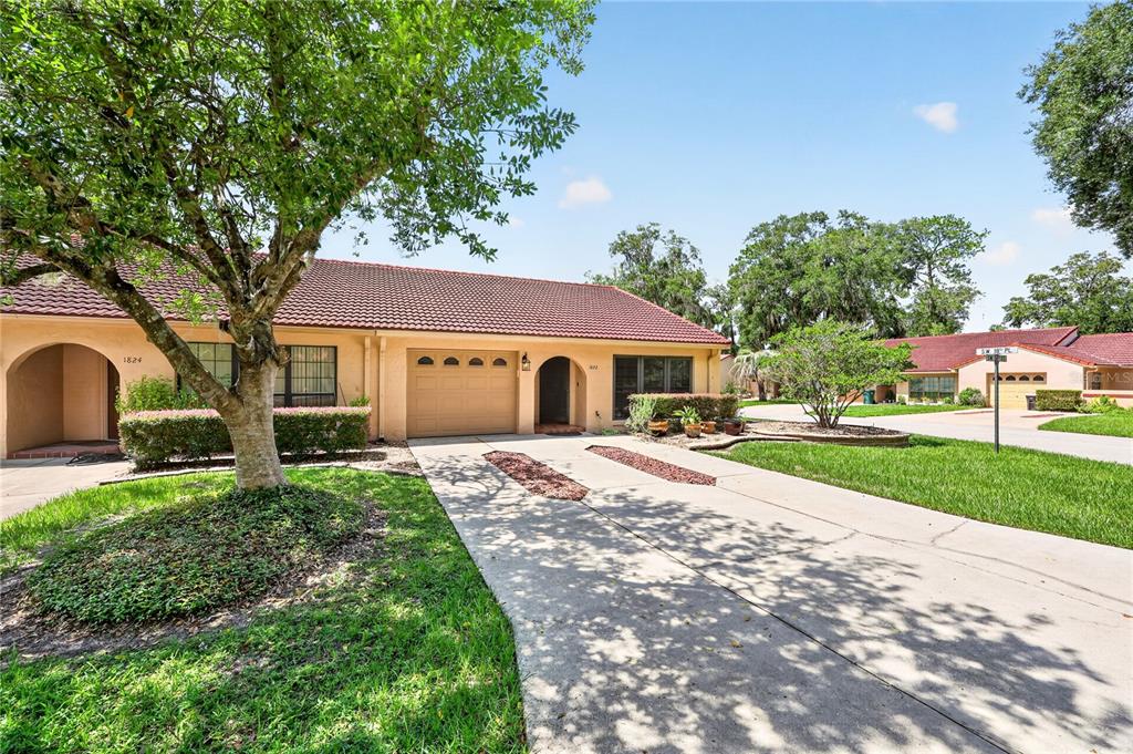 A single-story house with a tan stucco exterior, a red tile roof, and a concrete driveway — 1822 SW 34TH COURT, OCALA, FL
