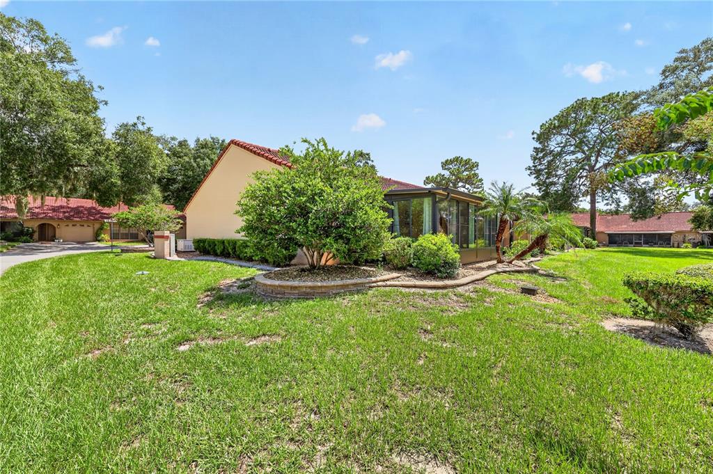 A tan house with a red tile roof and a screened-in porch sits on grass — 1822 SW 34TH COURT, OCALA, FL