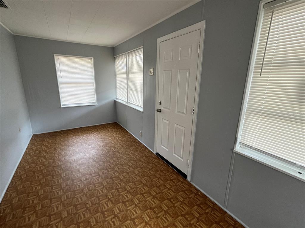 An empty room features gray walls, a patterned vinyl floor, and three windows with blinds — 403 8TH STREET NE, WINTER HAVEN, FL