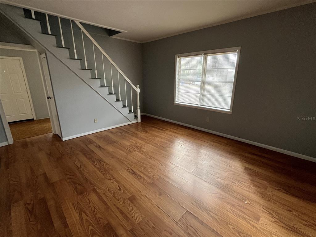 A living room features wood-look flooring, gray walls, and a staircase with a white railing — 403 8TH STREET NE, WINTER HAVEN, FL