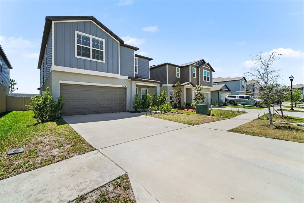A two-story house with blue siding and a concrete driveway under a clear sky — 35194 ACKLEY TRCE, ZEPHYRHILLS, FL