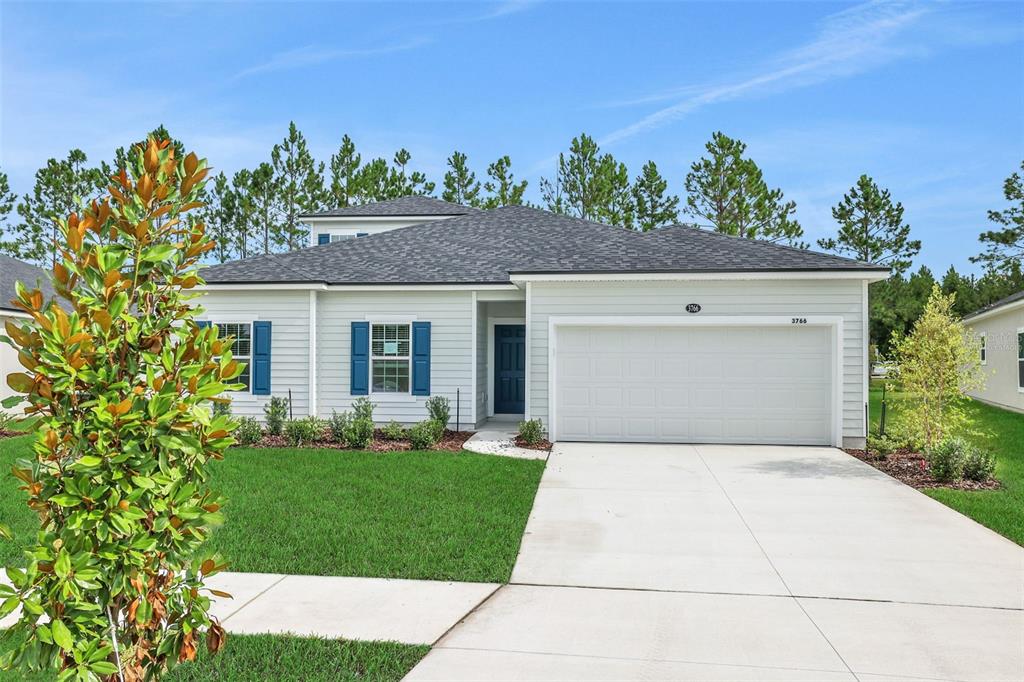A single-story house with light siding, blue shutters, a two-car garage, and a front lawn — 3754 HOLSTEIN WAY, GREEN COVE SPRINGS, FL